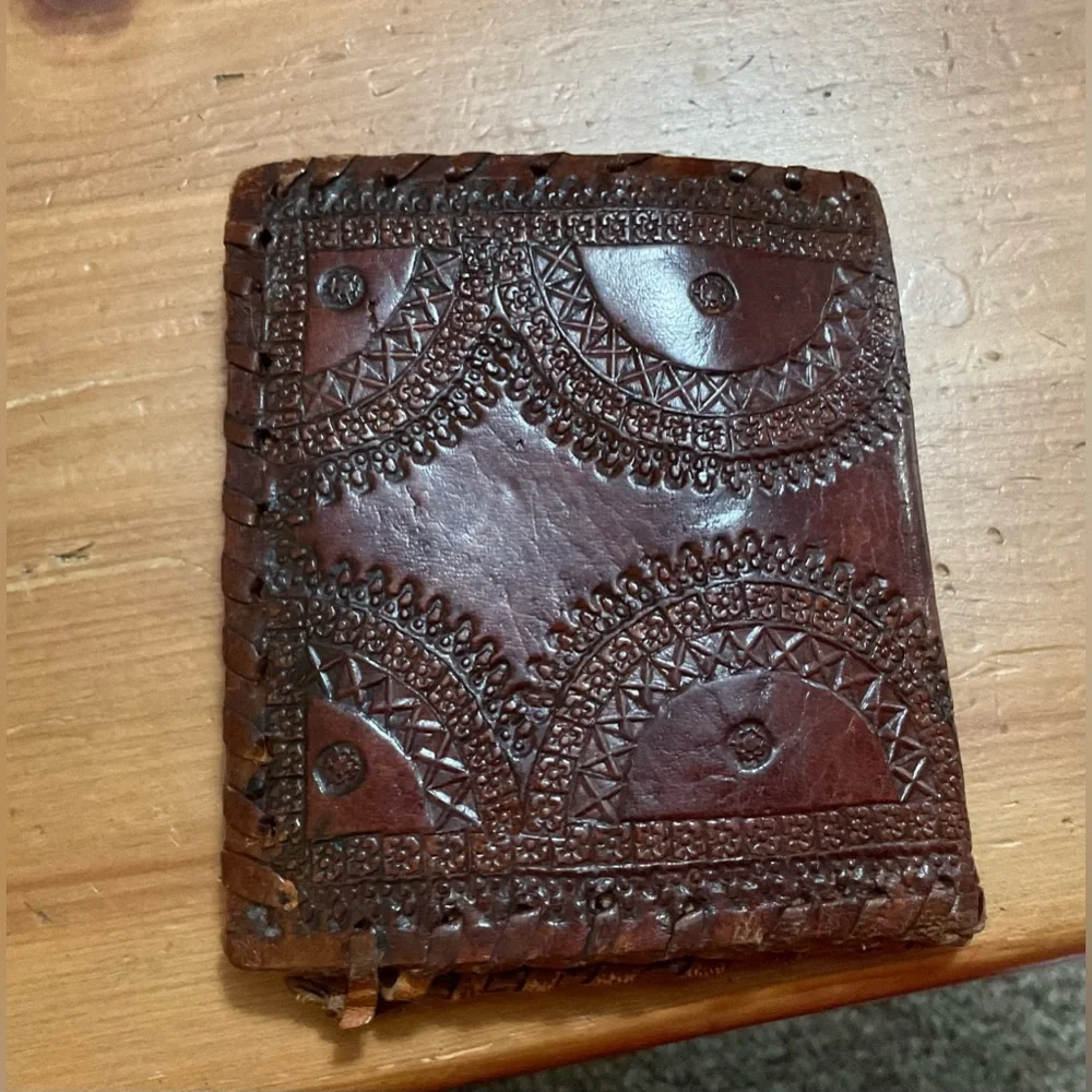 Hand crafted tooled mens leather design bifold wallet laced stitching around it.
